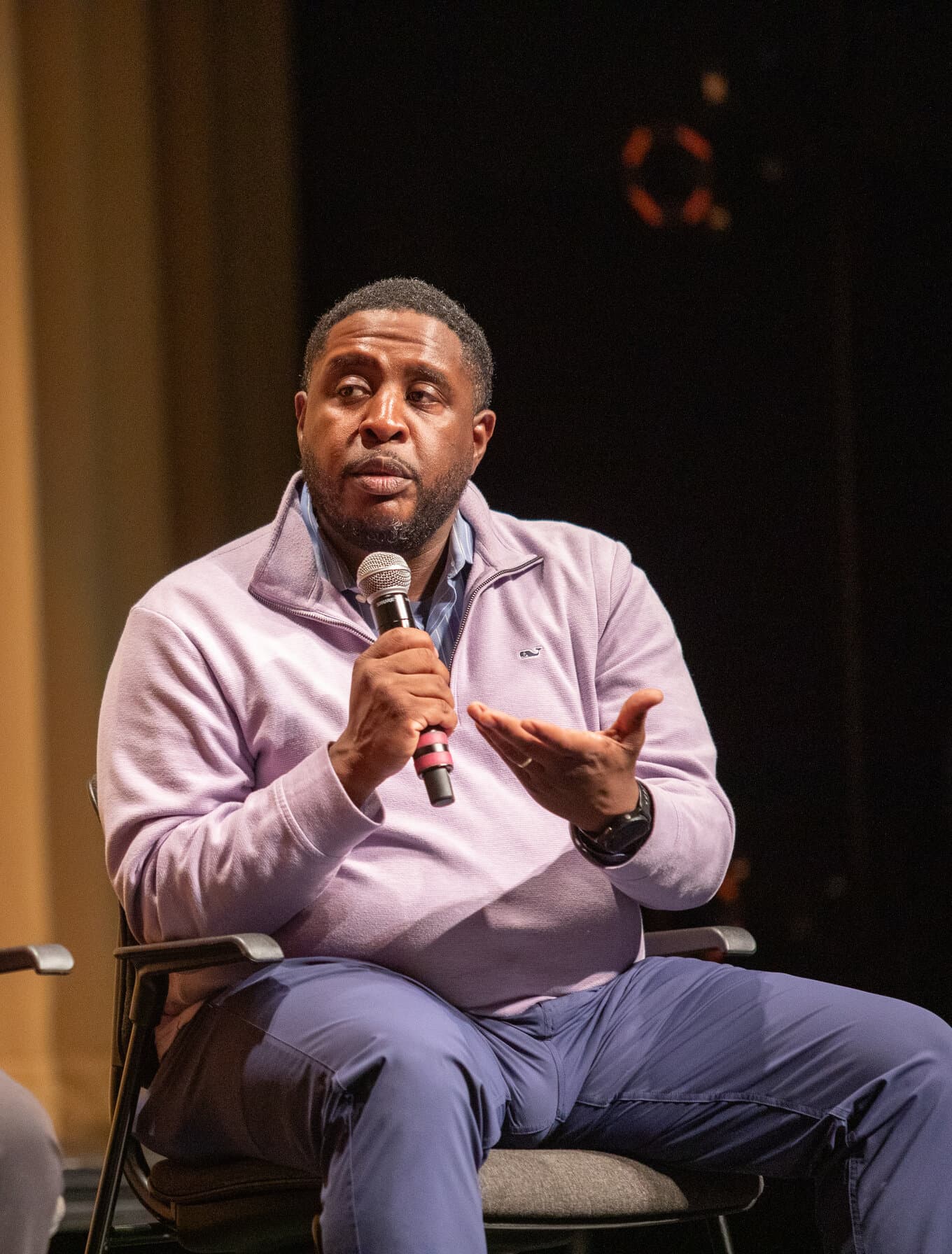 Christopher speaking into a microphone on stage at the Our Minds Matter panel